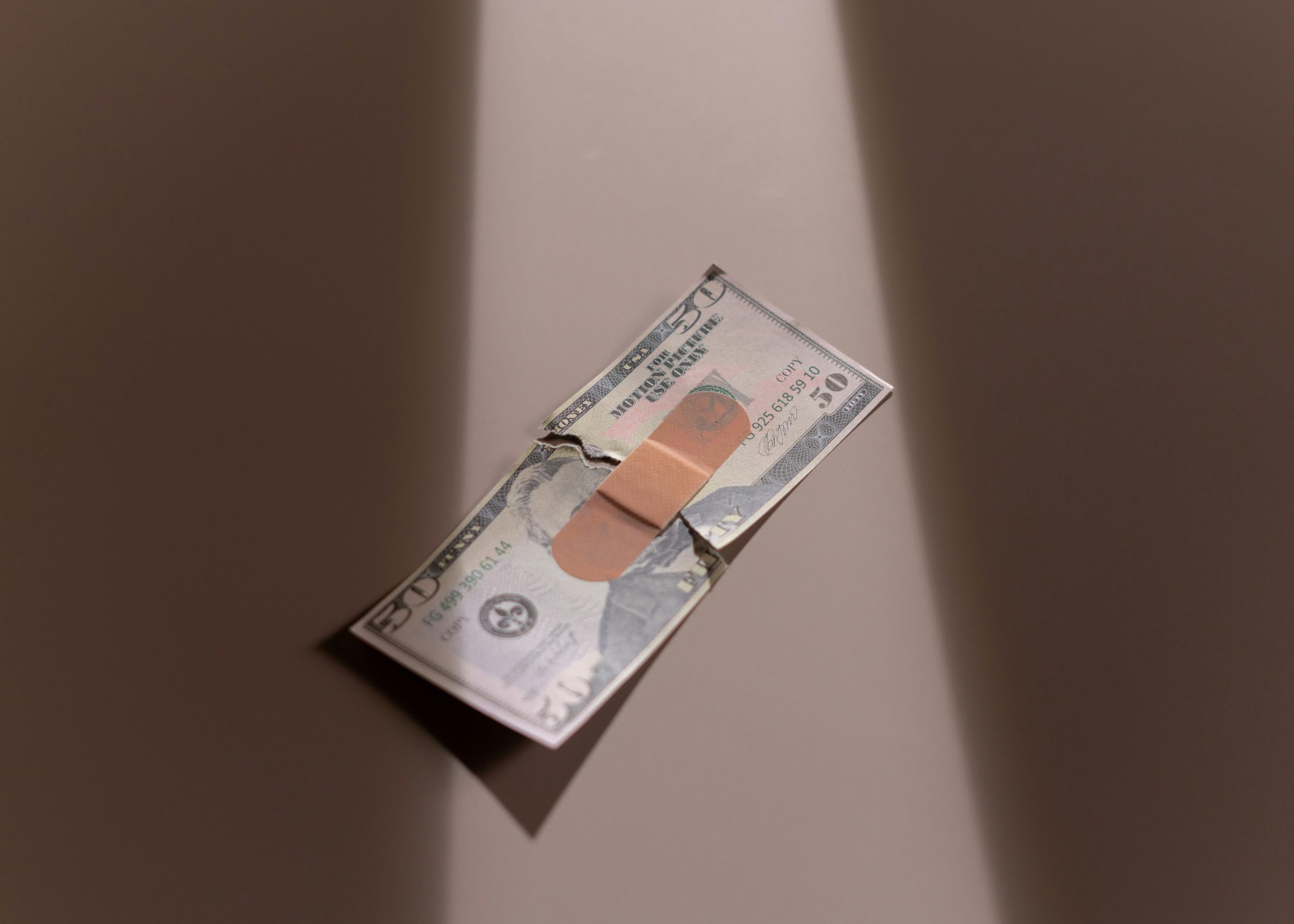 Home A $50 bill with a bandage symbolizes financial recovery and repair.